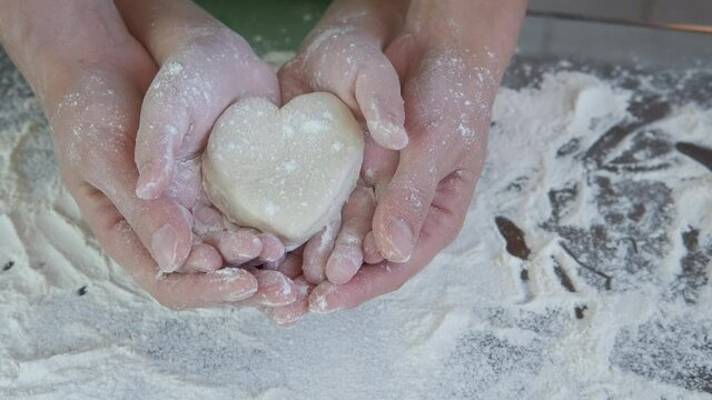 Heart made of flour. Hands of mother and child with heart from tes.