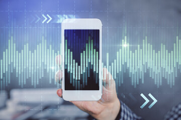 Double exposure of man's hands holding and using a digital device and forex graph drawing. Financial market concept.