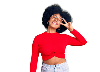 Young african american girl wearing casual clothes and glasses doing peace symbol with fingers over face, smiling cheerful showing victory