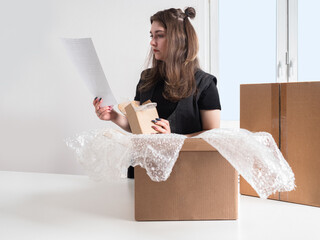 Online store. Dispatch of orders. A girl is packing goods for delivery. A woman formes the parcel....