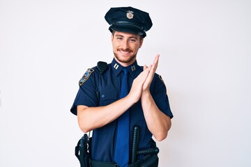 Young caucasian man wearing police uniform clapping and applauding happy and joyful, smiling proud hands together