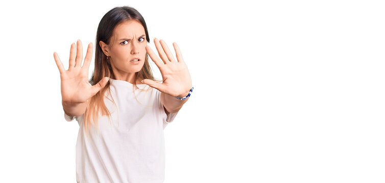 Beautiful caucasian woman wearing casual white tshirt doing stop gesture with hands palms, angry and frustration expression