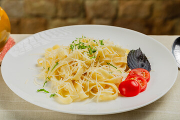 Fresh pasta on a white plate with tomatoes and cheese.