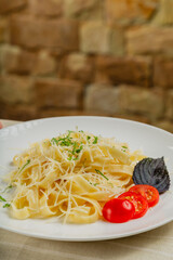 Fresh pasta on a white plate with tomatoes and cheese.