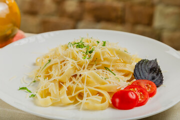 Fresh pasta on a white plate with tomatoes and cheese.