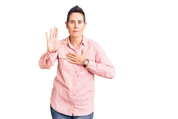 Young woman with short hair wearing casual clothes swearing with hand on chest and open palm,...