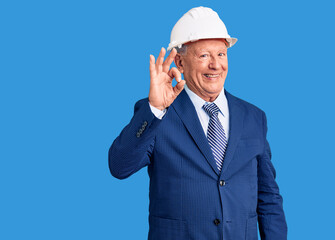 Senior handsome grey-haired man wearing suit and architect hardhat smiling positive doing ok sign with hand and fingers. successful expression.