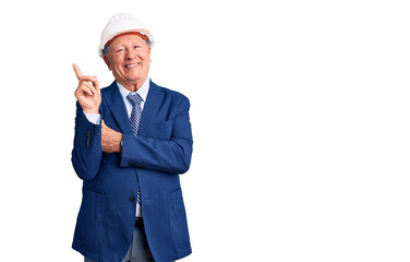 Senior handsome grey-haired man wearing suit and architect hardhat with a big smile on face, pointing with hand and finger to the side looking at the camera.