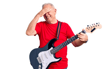 Senior handsome grey-haired man playing electric guitar stressed and frustrated with hand on head, surprised and angry face