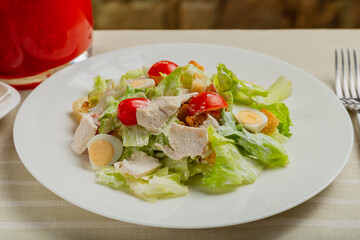 Fresh caesar salad in a white plate on the table.