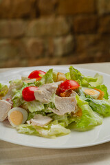 Fresh caesar salad in a white plate on the table.
