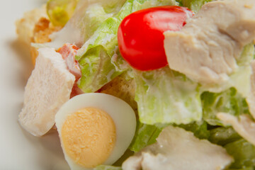 Fresh caesar salad in a white plate on the table.