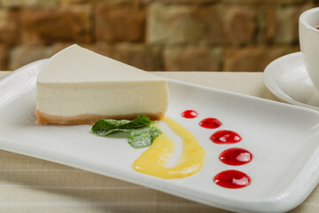 Fresh cheesecake on a white plate with jam in a restaurant.