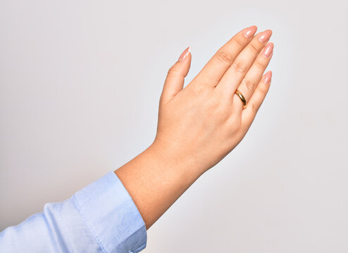 Hand of caucasian young woman holding golden marriage ring over isolated white background