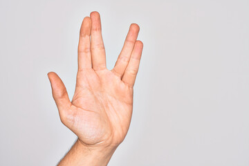Hand of caucasian young man showing fingers over isolated white background greeting doing Vulcan salute, showing hand palm and fingers, freak culture