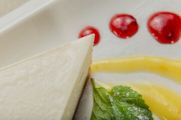 Fresh cheesecake on a white plate with jam in a restaurant.