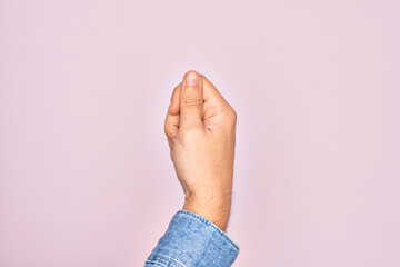 Hand of caucasian young man showing fingers over isolated pink background holding blank space with thumb finger, business and advertising