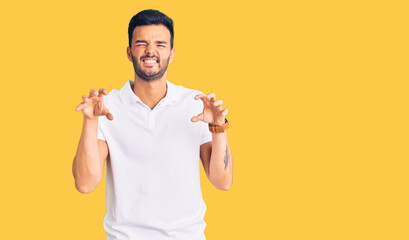 Young handsome hispanic man wearing casual clothes smiling funny doing claw gesture as cat,...