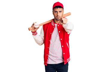 Young hispanic man playing baseball holding bat and ball pointing with finger to the camera and to you, confident gesture looking serious