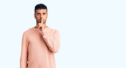 Fototapeta premium Young hispanic man wearing casual clothes asking to be quiet with finger on lips. silence and secret concept.