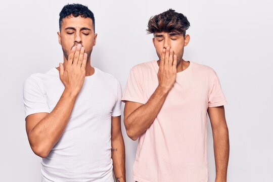 Young gay couple wearing casual clothes bored yawning tired covering mouth with hand. restless and sleepiness.