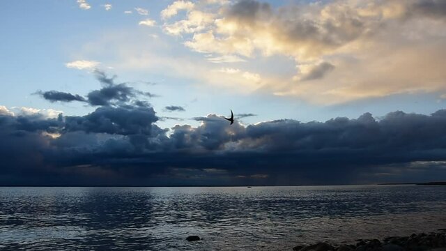 The sea after a storm over the Swedish Baltic Sea at sunset where the sun's rays light up between the clouds and the sky starts to turn blue again late at night