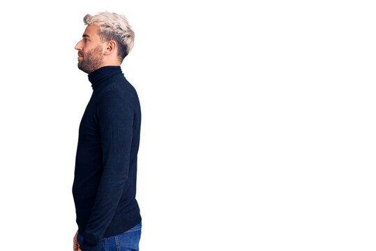 Young handsome blond man wearing casual turtleneck sweater looking to side, relax profile pose with natural face with confident smile.