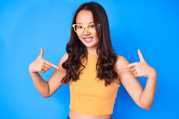Young beautiful chinese girl wearing casual clothes and glasses looking confident with smile on...