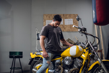 A brutal biker buys a yellow powerful motorcycle. He checks it in the garage