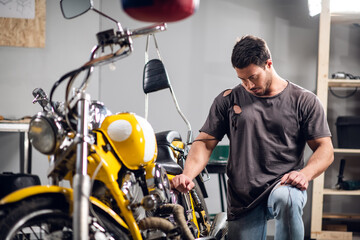 Fototapeta na wymiar Private vehicle repair shop. Tuning a yellow chopper by a young mechanic