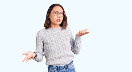 Young beautiful chinese girl wearing casual clothes clueless and confused with open arms, no idea...
