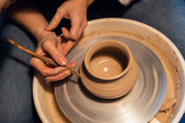 a master in a pottery workshop shows the technique of modeling a pot on a Potter's wheel