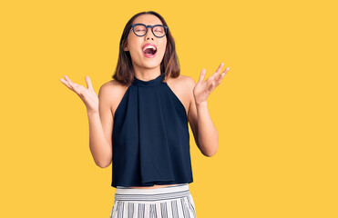 Young beautiful chinese girl wearing casual clothes and glasses celebrating mad and crazy for...