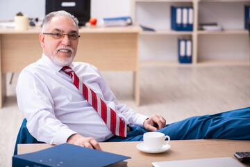 Old male employee enjoying coffee during coffee break