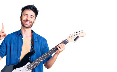Obraz premium Young hispanic man playing electric guitar surprised with an idea or question pointing finger with happy face, number one