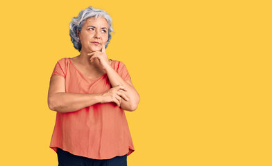 Senior woman with gray hair wearing orange tshirt serious face thinking about question with hand on...