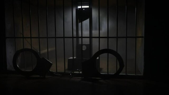 Execution concept. Death penalty guillotine miniature inside old prison. Old prison bars cell lock. Man inside jail. Horror view of Guillotine scale model in the dark