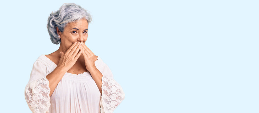 Senior woman with gray hair wearing bohemian style laughing and embarrassed giggle covering mouth with hands, gossip and scandal concept