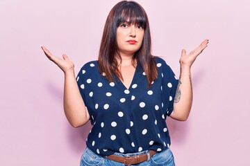 Young plus size woman wearing casual clothes clueless and confused with open arms, no idea and...