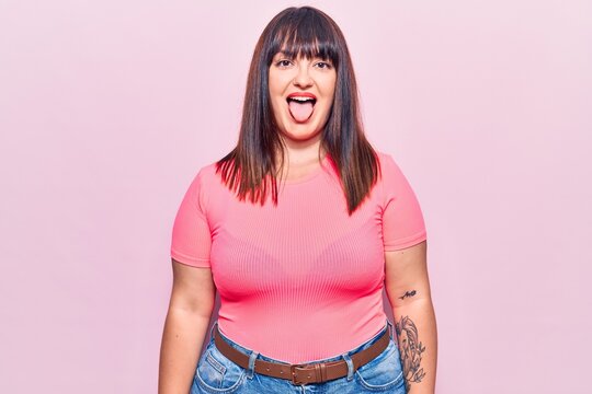 Young plus size woman wearing casual clothes sticking tongue out happy with funny expression. emotion concept.