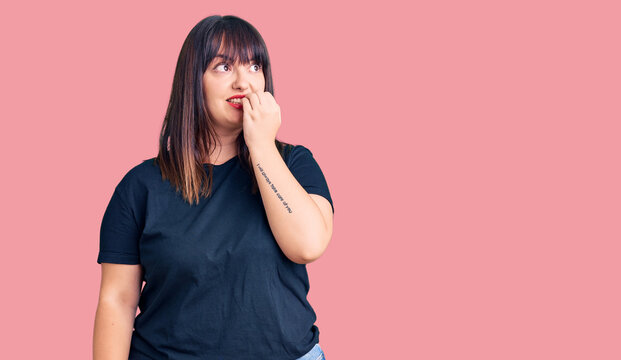 Young plus size woman wearing casual clothes looking stressed and nervous with hands on mouth biting nails. anxiety problem.