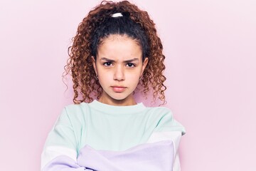 Beautiful kid girl with curly hair wearing casual clothes skeptic and nervous, disapproving expression on face with crossed arms. negative person.