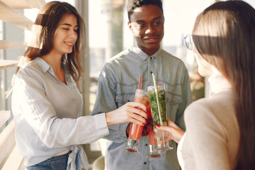 Black man in a cafe. International people. Man in a blue shirt. Women drinking a cocktails.