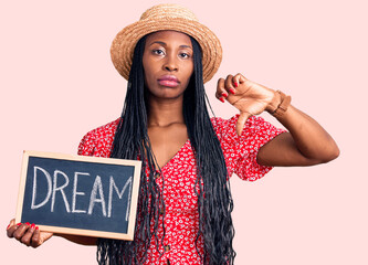 Young african american woman holding blackboard with dream word with angry face, negative sign...