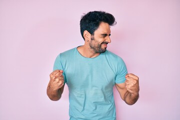 Handsome hispanic man with beard wearing casual clothes excited for success with arms raised and eyes closed celebrating victory smiling. winner concept.