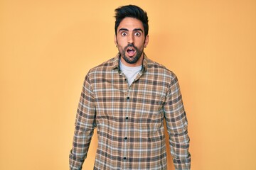 Handsome hispanic man with beard wearing casual clothes afraid and shocked with surprise expression, fear and excited face.