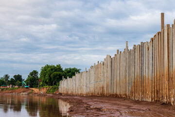 Numerous concrete pillars form a wall to protect the riverbank.