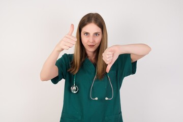 Female doctor wearing a green scrubs and stethoscope showing thumbs up and thumbs down, difficult...
