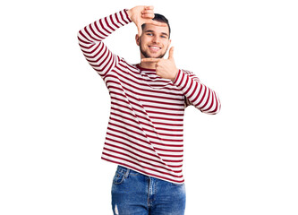 Young handsome man wearing striped sweater smiling making frame with hands and fingers with happy face. creativity and photography concept.