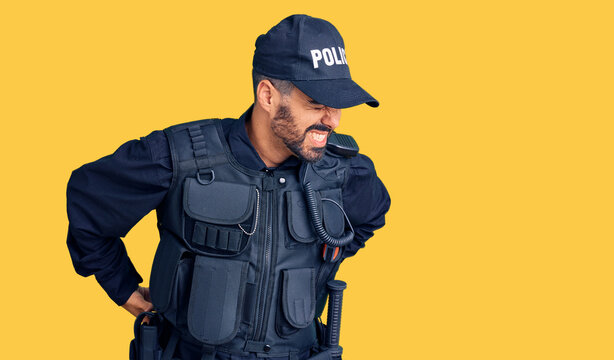 Young hispanic man wearing police uniform suffering of backache, touching back with hand, muscular pain